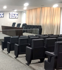 Cortinas &agrave; direia com as cadeiras do audit&oacute;rio e, ao fundo, parte do plen&aacute;rio com monitores ligados